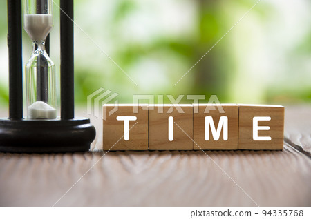 Time text on wooden blocks with minute glass and blurred nature background. Time concept 94335768