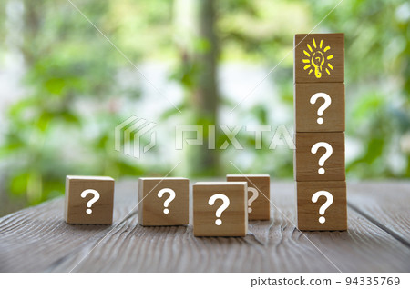 Wooden cube block with light bulb surrounded by questions marks. Solution and idea concept Wooden cube block with light bulb surrounded by questions marks. Solution and idea concept 94335769