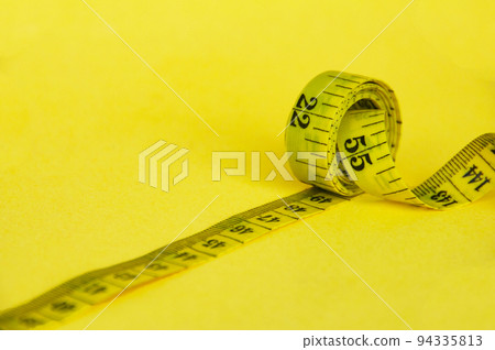 Yellow measuring tape with customizable space for text or ideas. Copy space and weight loss concept Yellow measuring tape with customizable space for text or ideas. Copy space and weight loss concept 94335813