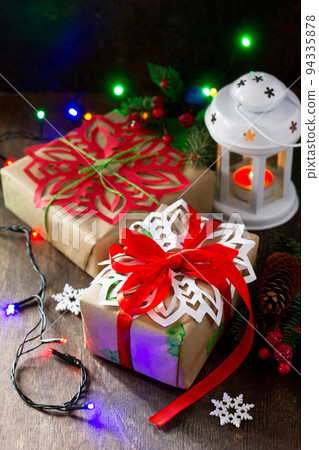 Merry Christmas concept. Packing presents for Christmas in handmade boxes, fir tree, present and decorations on wooden table. Copy space. Merry Christmas concept. Packing presents for Christmas in handmade boxes, fir tree, present and decorations on wooden table. Copy space. 94335878