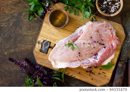 Fresh raw meat. Raw pork meat fillet with olive oil, spices and fresh basil on rustic wooden table. Top view flat lay background. Copy space. Fresh raw meat. Raw pork meat fillet with olive oil, spices and fresh basil on rustic wooden table. Top view flat lay background. Copy space. 94335879