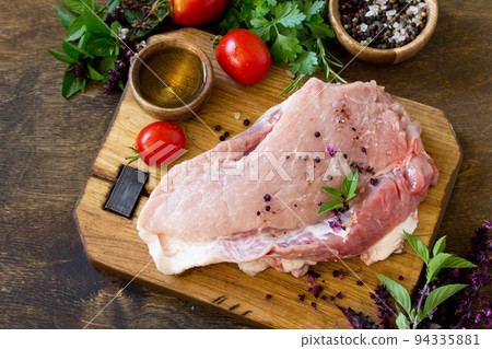 Fresh raw meat. Raw pork meat fillet with tomatoes, olive oil, spices and fresh basil on rustic wooden table. Fresh raw meat. Raw pork meat fillet with tomatoes, olive oil, spices and fresh basil on rustic wooden table. 94335881