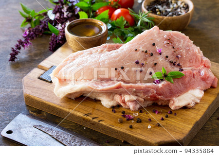 Fresh raw meat. Raw pork meat fillet with tomatoes, olive oil, spices and fresh basil on rustic wooden table. Fresh raw meat. Raw pork meat fillet with tomatoes, olive oil, spices and fresh basil on rustic wooden table. 94335884
