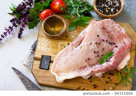 Fresh raw meat. Raw pork meat fillet with tomatoes, olive oil, spices and herbs on wooden table. Copy space. Fresh raw meat. Raw pork meat fillet with tomatoes, olive oil, spices and herbs on wooden table. Copy space. 94335889