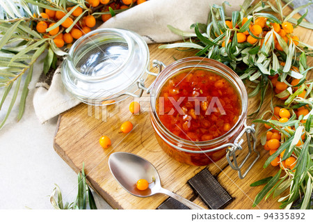 Homemade jam. Glass jar with sea buckthorn jam on rustic background. Preserved berry. Copy space. Homemade jam. Glass jar with sea buckthorn jam on rustic background. Preserved berry. Copy space. 94335892