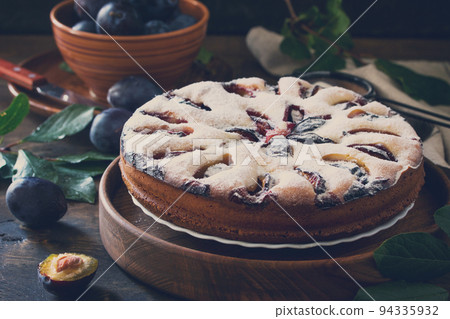 Delicious dessert plum pie, sweet delicious holiday cake with plums on wooden table. Toned image. 94335932