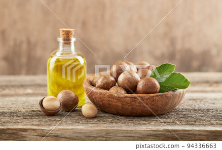 Macadamia nuts with oil on old wooden background Macadamia nuts with oil on old wooden background 94336663