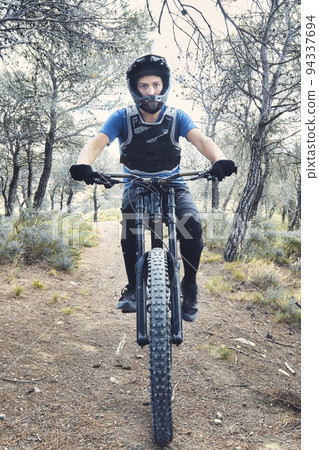Teenager in forest practicing downhill biking. Teenager in forest practicing downhill biking. 94337694