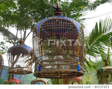 MELAKA, MALAYSIA -JUNE 7, 2022: Traditional bird cages made of bamboo are hung in an open area. Has a fabric cover to protect the bird inside from the weather. Displayed for exhibition. MELAKA, MALAYSIA -JUNE 7, 2022: Traditional bird cages made of bamboo are hung in an open area. Has a fabric cover to protect the bird inside from the weather. Displayed for exhibition. 94337853