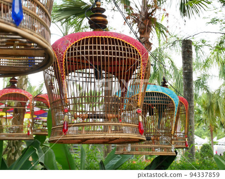 MELAKA, MALAYSIA -JUNE 7, 2022: Traditional bird cages made of bamboo are hung in an open area. Has a fabric cover to protect the bird inside from the weather. Displayed for exhibition. 94337859
