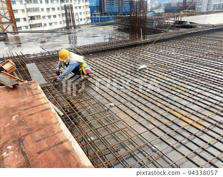 MELAKA, MALAYSIA -JULY 1, 2022: Construction workers are fabricating steel reinforcement bars for floor slabs. Rebar of various sizes is arranged and tied according to the design by the engineer. MELAKA, MALAYSIA -JULY 1, 2022: Construction workers are fabricating steel reinforcement bars for floor slabs. Rebar of various sizes is arranged and tied according to the design by the engineer. 94338057