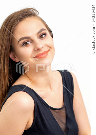 Portrait of a beautiful young caucasian smiling brunette woman with long straight hair standing and looking at the camera on white background 94339434