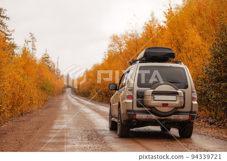SUV on scenic autumn road in the forest 94339721