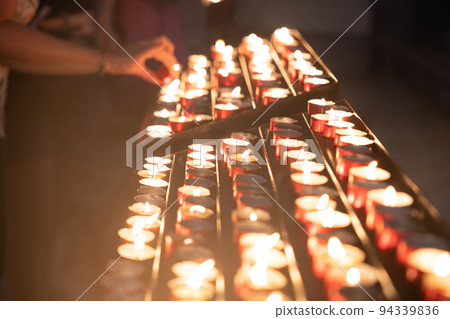 Several candles lined up in church closeup Several candles lined up in church closeup 94339836