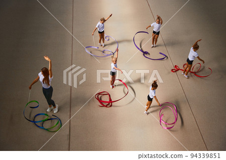 Aerial view. Female sports coach training gymnastics athletes at sports gym, indoors. Concept of sport, studying, art, education Aerial view. Female sports coach training gymnastics athletes at sports gym, indoors. Concept of sport, studying, art, education 94339851