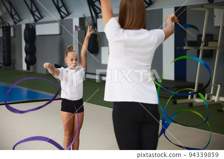 Coaching. Beginner gymnastics athletes doing exercises with gymnastics equipment at sports gym, indoors. Concept of sport, studying, art, education 94339859