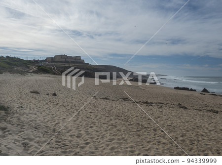 View of empty Praia da Ilha do Pessegueiro sand beach with ocean waves and small fortress and restaurant at Rota Vicentina coast near Porto Covo, Portugal. View of empty Praia da Ilha do Pessegueiro sand beach with ocean waves and small fortress and restaurant at Rota Vicentina coast near Porto Covo, Portugal. 94339999