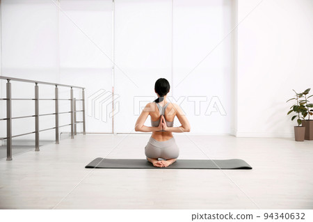 Young woman practicing seiza asana in yoga studio, back view. Vajrasana pose 94340632