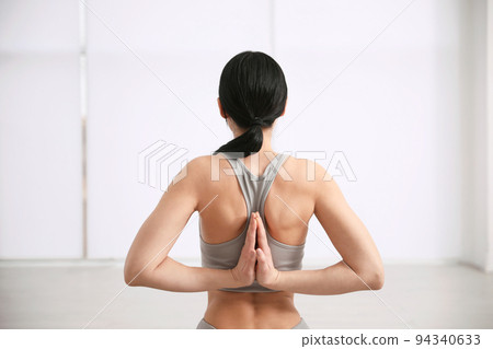 Young woman practicing seiza asana in yoga studio, back view. Vajrasana pose 94340633