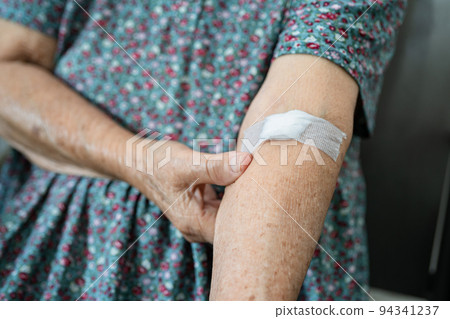 Asian senior or elderly old lady woman patient show cotton wool stop bleeding, after blood drawing testing for annually physical health check up to check cholesterol, blood pressure, and sugar level. 94341237