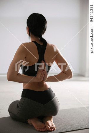 Young woman practicing seiza asana in yoga studio, back view. Vajrasana pose 94341351