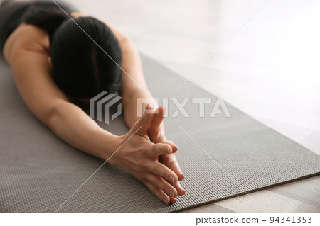 Young woman practicing extended child's asana in yoga studio, closeup. Utthita Balasana pose Young woman practicing extended child's asana in yoga studio, closeup. Utthita Balasana pose 94341353
