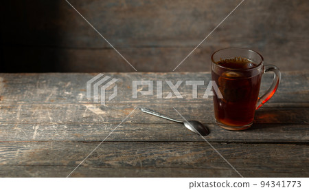 A cup of tea with a sachet on a wooden background. 94341773