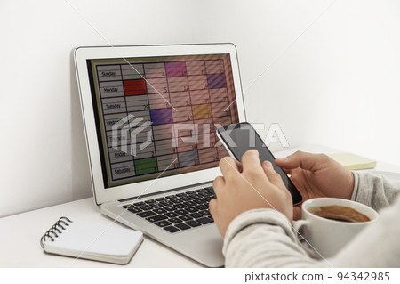 Young man using calendar app on laptop in office, closeup Young man using calendar app on laptop in office, closeup 94342985