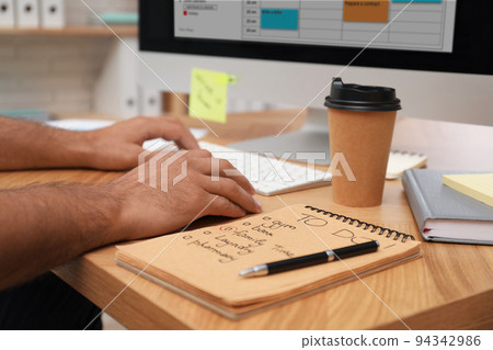 Man planning his schedule with calendar app on computer in office, closeup Man planning his schedule with calendar app on computer in office, closeup 94342986