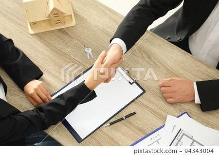 Real estate agent shaking hands with client at table in office, above view Real estate agent shaking hands with client at table in office, above view 94343004