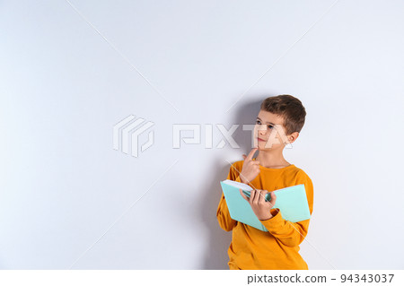 Cute little boy with book on light background, space for text Cute little boy with book on light background, space for text 94343037