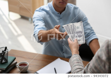 Woman giving bribe money to man at table, closeup Woman giving bribe money to man at table, closeup 94343072