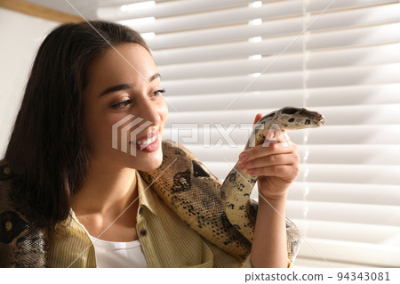 Young woman with her boa constrictor at home. Exotic pet 94343081