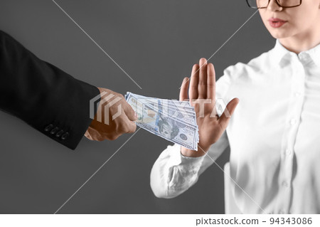 Woman refuses to take bribe money on dark background, closeup Woman refuses to take bribe money on dark background, closeup 94343086