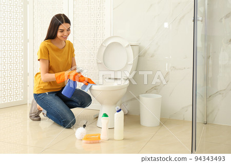 Young woman cleaning toilet bowl in bathroom Young woman cleaning toilet bowl in bathroom 94343493