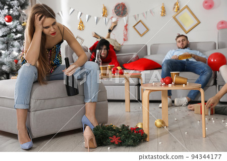 Friends suffering from hangover in messy room after New Year party 94344177