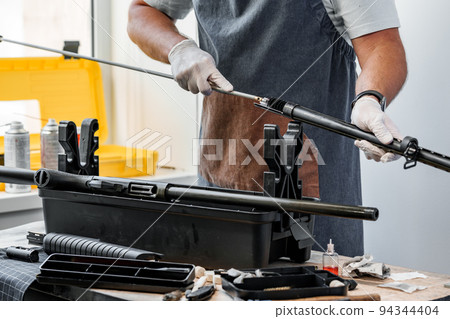 Close up of a gunsmith cleaning firearm barrel with ramrod brush Close up of a gunsmith cleaning firearm barrel with ramrod brush 94344404
