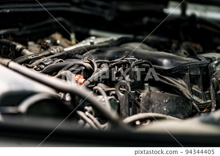 View of engine and other parts under the open hood of a car View of engine and other parts under the open hood of a car 94344405