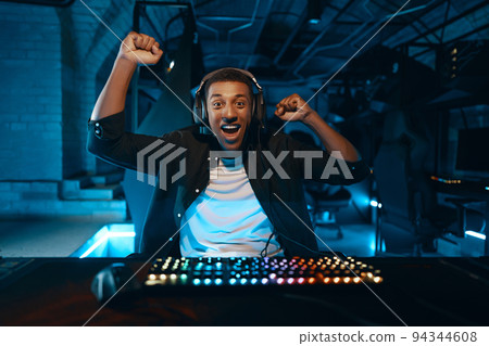 Lucky guy won the game. A cyber gamer is playing in a neon room. 94344608