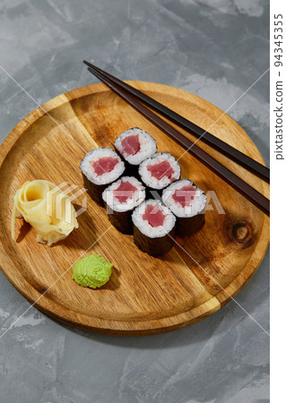 Different types of delicious and juicy sushi and rolls on a wooden board Different types of delicious and juicy sushi and rolls on a wooden board 94345355