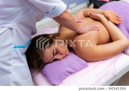 Blonde massage therapist massaging a woman. Woman getting a massage at the spa Blonde massage therapist massaging a woman. Woman getting a massage at the spa 94345384