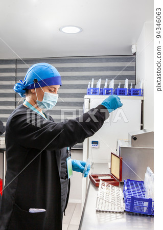 Young female scientist preparing slides for karyotipe and fluorescence in situ hybridization at the laboratory 94346063
