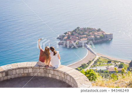 Two Woman tourist on background of beautiful view of the island of St. Stephen, Sveti Stefan on the Budva Riviera, Budva, Montenegro. Travel to Montenegro concept Portrait of a disgruntled girl Two Woman tourist on background of beautiful view of the island of St. Stephen, Sveti Stefan on the Budva Riviera, Budva, Montenegro. Travel to Montenegro concept Portrait of a disgruntled girl 94346249