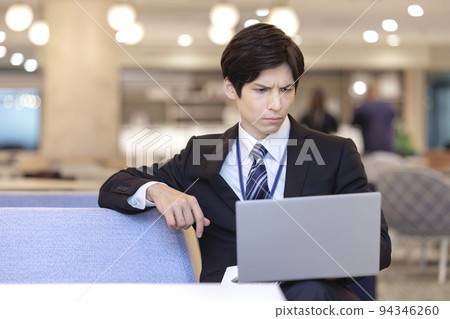 A businessman operating a laptop computer 94346260