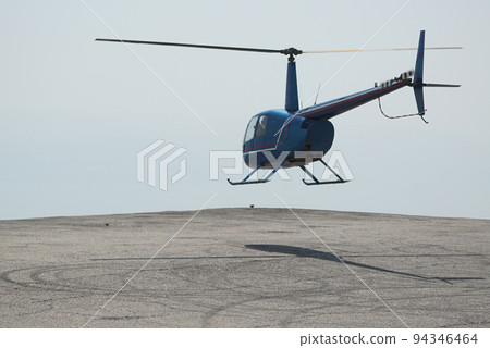 Blue helicopter flying in grey cloudy skies 94346464
