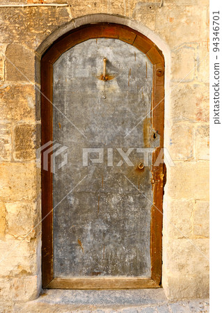 Silver colored metal door inside of stone wall Silver colored metal door inside of stone wall 94346701