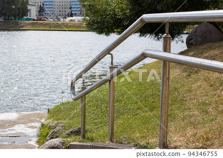 Metal railings at the stairs near the pond 94346755