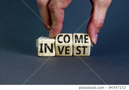 Invest or income symbol. Concept words Invest and Income on wooden cubes. Businessman hand. Beautiful grey table grey background. Business and invest or income concept. Copy space. 94347152