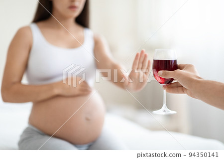 Cropped of young pregnant woman refuses to drink wine 94350141