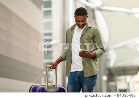 Happy Black Man Using Phone With Travel Application At Airport Happy Black Man Using Phone With Travel Application At Airport 94350492